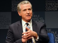 Gavin Newsom apregoa o ‘plano hídrico mais ambicioso’ da história da Califórnia A água flui de cinco portões na represa Shasta, com um lago atrás e montanhas nevadas ao longe.