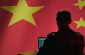 Hackers do Salt Typhoon da China invadiram empresas norueguesas A man sits in front of a computer and the Chinese flag.