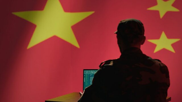 Hackers do Salt Typhoon da China invadiram empresas norueguesas A man sits in front of a computer and the Chinese flag.