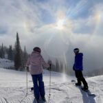 Dois esquiadores na montanha Whitefish são banhados pela refração da luz solar através de cristais de gelo, um fenômeno chamado