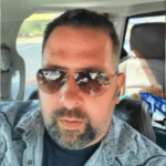 Homem de Lexington pega pena de prisão em esquema federal de fraude em empréstimos de jogos de azar COVID-19. Homem barbudo de óculos escuros sentado em um carro