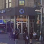 Vista da rua West 125 Street e St. Nicholas Avenue na cidade de Nova York, com uma agência bancária Chase e uma entrada de estação de metrô.