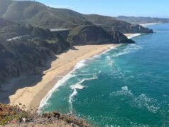 Horror quando uma pessoa cai de 250 pés para a morte do famoso penhasco ‘Devil’s Slide’ Grey Whale Cove State Beach, no condado de San Mateo, Califórnia, mostrando ondas quebrando contra a costa rochosa abaixo de um penhasco alto com um prédio no topo.