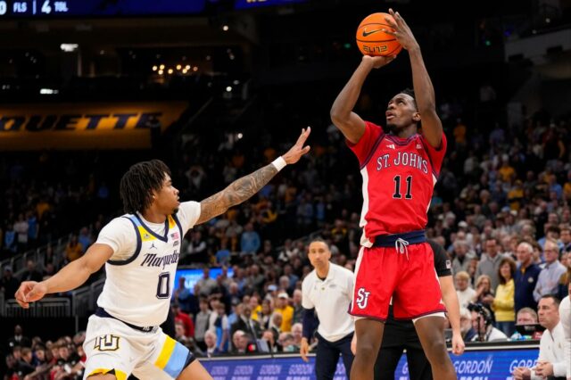 O guarda do St. John's Red Storm, Ian Jackson (11), atira sobre o guarda do Marquette Golden Eagles, Nigel James Jr.