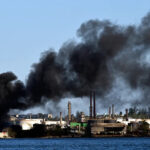 coluna de fumaça subindo da refinaria Nico Lopez, na Baía de Havana, embora não se soubesse se o incêndio ocorreu perto dos tanques de armazenamento de petróleo da usina. (Foto de YAMIL LAGE/AFP)