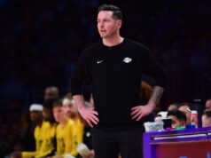 JJ Redick assa a jaqueta de Luka Dončić durante a vitória do Lakers sobre o Mavericks O técnico do Los Angeles Lakers, JJ Redick, ausente durante um jogo.