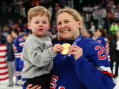 Kendall Coyne Schofield, dos EUA, compartilha um adorável momento no gelo com o filho após ganhar o ouro olímpico Medalhista de ouro Kendall Coyne, vestindo uma camisa azul com
