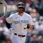 Um jogador de beisebol do Colorado Rockies, uniformizado, com capacete e óculos escuros, corre em campo.