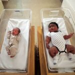 Dois recém-nascidos de tamanhos muito diferentes em berços hospitalares.