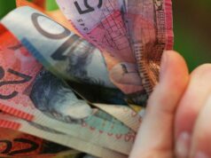 Mais de cinco milhões de australianos receberão aumento de caixa em apenas algumas semanas Alguém segurando um punhado de dinheiro australiano.