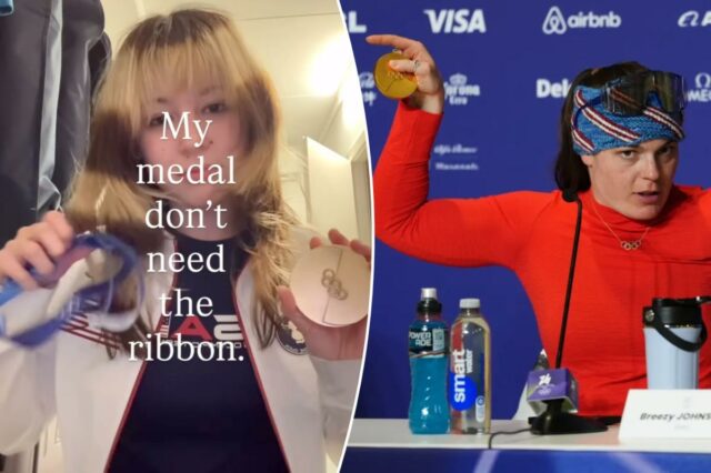 Uma pessoa com uma jaqueta esportiva branca e azul segura uma medalha olímpica.