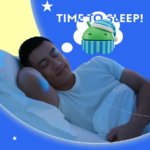 Uma pessoa dormindo na cama com um telefone na mesa de cabeceira mostrando um mascote andróide dormindo usando uma bebida antes de dormir.