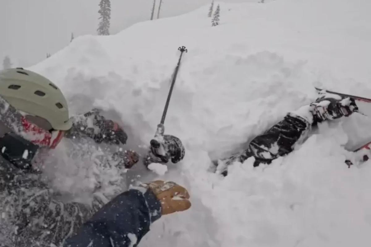 Momento de parar o coração: esquiador é resgatado após ser enterrado vivo sob uma montanha de neve no Lago Tahoe Três pessoas apanhadas por uma avalanche estão parcialmente cobertas de neve, com um bastão de esqui espetado na neve.