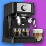 Máquina de café expresso De'Longhi preta com dois copos de café expresso e um copo de café com leite.