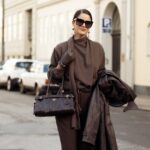 LONDRES, INGLATERRA - 19 DE SETEMBRO: Jill Asemota vista usando um elegante óculos de sol Miu Miu em preto brilhante, um blazer de couro de camurça marrom chocolate da Zara, cortado em uma silhueta descontraída com mangas ligeiramente grandes e bolsos com aba nas laterais, elegante top Wolford preto justo em um design minimalista, minissaia Burberry Vintage em um padrão xadrez bege e marrom, sob medida para um corte reto, meia-calça preta transparente, Chanel Mary preta clássica Sapatilhas Jane, confeccionadas em couro liso e bolsa vintage preta estruturada, formato quadradão com alças curtas e detalhes de ferragens metálicas. Seu cabelo castanho está penteado em um penteado longo e reto com sutis mechas caramelo, repartido naturalmente e caindo sobre os ombros, durante a London Fashion Week em 19 de setembro de 2025 em Londres, Inglaterra. (Foto de Jeremy Moeller/Getty Images)