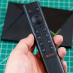 Uma estatueta de bot Android de costas para a Nvidia Shield TV, olhando para um Google TV Streamer.