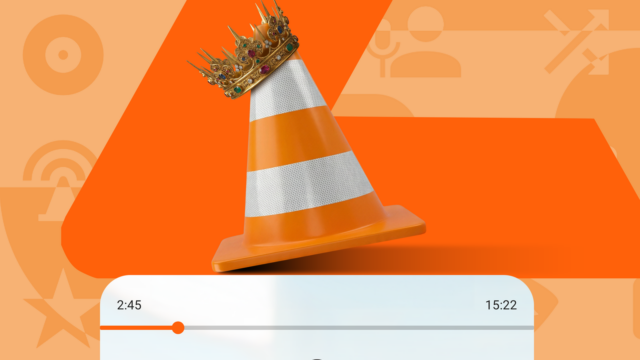 Mascote Android verde espiando por trás de um grande cone de trânsito VLC laranja em um fundo estampado.