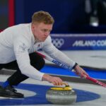 Bobby Lammie, da Grã-Bretanha, lança uma pedra de curling enquanto segura uma vassoura durante uma partida de curling.