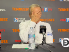 O técnico do Tennessee, Rick Barnes, faz piada sobre jogadores apostando em jogos Close do técnico do Tennessee, Rick Barnes, em uma coletiva de imprensa, mesa e microfone à sua frente. Sua mão está cobrindo seu rosto.