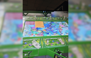 Oito presos enquanto cassino ilegal é fechado pela polícia na Pensilvânia Oito presos porque um cassino ilegal foi fechado pela polícia na Pensilvânia. Close de uma mesa de jogo de cassino ilegal apreendida durante uma operação policial, mostrando uma superfície de jogo colorida com gráficos com tema subaquático, dinheiro espalhado, fichas estilo pôquer e pequenas estatuetas, com partes da máquina abertas e fiação exposta, indicando que ela foi desligada e confiscada.