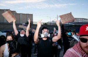 Os ativistas anti-ICE são uma insurgência, não um movimento de protesto Os manifestantes seguram cartazes que dizem