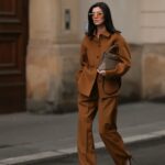 Alba Garavito Torre usa óculos de sol pretos da Ray Ban, brincos grandes com pingente dourado e branco, uma camiseta preta, um pulôver de lã branco com listras pretas da Massimo Dutti, uma bolsa de ombro Timeless de couro granulado preto brilhante da Chanel, uma jaqueta blazer preta oversized da Munthe, calça jeans skinny branca da Zara, couro bege brilhante com biqueira preta da Chanel, durante uma sessão de fotos de moda street style, em 29 de abril de 2023 em Paris, França.