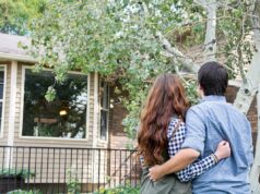 Os principais erros que os proprietários cometem depois de pagar a hipoteca – e como evitá-los Casal visto por trás, se abraçando enquanto olha para sua nova casa.