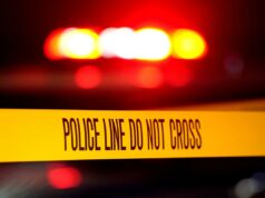 Pai demente de Nova York hackeia esposa e filha e depois se mata a facadas A linha policial não cruza a fita em uma cena de crime com luzes vermelhas piscando ao fundo.