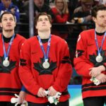 MILÃO, ITÁLIA - 22 DE FEVEREIRO: O nº 74 dos EUA Jaccob Slavin (2L) e o nº 17 do Canadá Macklin Celebrini disputam o disco durante a partida masculina de hóquei no gelo pela medalha de ouro entre Canadá e EUA na Arena de Hóquei no Gelo Milano Santagiulia durante os Jogos Olímpicos de Inverno de Milano Cortina 2026 em 22 de fevereiro de 2026 em Milão, Itália. (Foto de Julien de Rosa - Piscina/Getty Images)