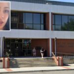 Uma mulher de longos cabelos negros, vestindo uma camisa de ombros largos, olha diretamente para a câmera com a boca ligeiramente aberta.