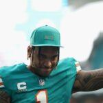 Tua Tagovailoa é demitida por Payton Wilson e Alex Highsmith durante um jogo de futebol americano da NFL.