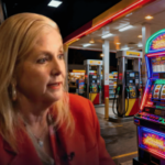 O procurador-geral do Missouri ordena a remoção de máquinas de jogos ilegais em todo o estado em meio à repressão. A procuradora-geral do Missouri, Hanaway, de blazer vermelho, fica em um posto de gasolina bem iluminado à noite, com bombas de combustível ao fundo e uma máquina de jogos colorida estilo caça-níqueis iluminada ao lado dela.