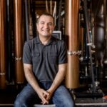 Melkon Khosrovian, proprietário da Destilaria Greenbar, sentado em frente ao equipamento da destilaria.