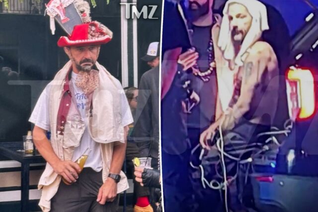 Shia LaBeouf, parecendo embriagado, vestido com um chapéu vermelho e branco com livro falso e acabamento fofo, camiseta branca, colete vermelho e bege e calça escura, segurando uma garrafa de cerveja.