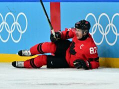 Sidney Crosby fora do jogo da medalha de ouro olímpica no Canadá, esmagador de lesões O jogador de hóquei no gelo Sidney Crosby com uma camisa vermelha com o número 87, deitado no gelo após uma lesão.