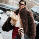 COPENHAGUE, DINAMARCA - 03 DE DEZEMBRO: Gili Biegun usa calças de alfaiataria marrons, malha marrom com lenço da Massimo Dutti, óculos de sol Celine, casaco longo oversized de couro marrom da Herskind, bolsa Prada Brown, luvas de couro Strathberry Brown em 03 de dezembro de 2024 em Copenhague, Dinamarca. (Foto de Raimonda Kulikauskiene/Getty Images)