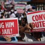 O padre católico padre Flavie Villanueva (R) dá as mãos aos parentes dos assassinatos extrajudiciais do ex-presidente filipino Rodrigo Duterte na guerra às drogas durante os ritos de posse no