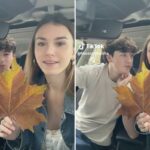 Dois adolescentes em um carro, um menino à esquerda olhando para uma menina à direita, que segura uma grande folha de outono.