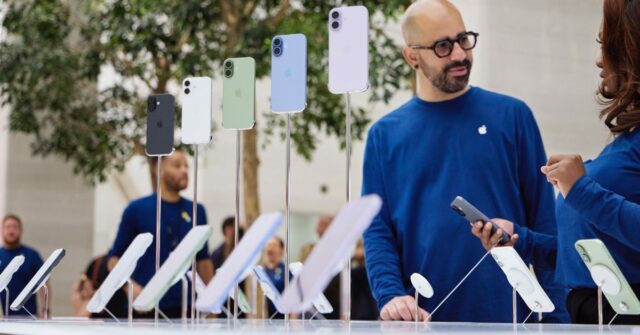 Tim Cook não descartou aumentos de preços dos produtos Apple, e este é o motivo | A foto mostra funcionários conversando atrás de uma tela de iPhones em uma loja da Apple