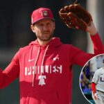 Trea Turner, do Philadelphia Phillies, com um moletom vermelho dos Phillies e um chapéu segurando uma luva de beisebol.