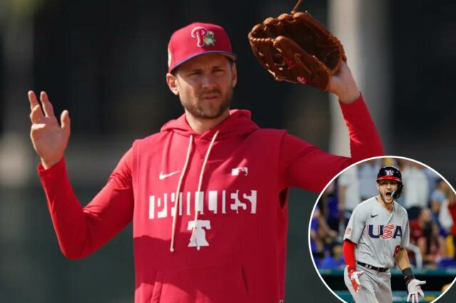 Trea Turner, do Philadelphia Phillies, com um moletom vermelho dos Phillies e um chapéu segurando uma luva de beisebol.