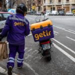 Getir delivery driver holding grocery bags and walking to Getir delivery bike
