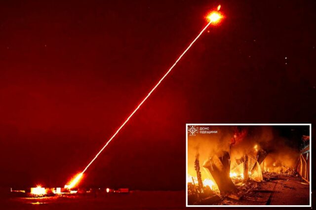 Um raio laser vermelho brilhante sai de um lançador terrestre em direção a um alvo no céu noturno.