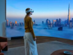 visionOS 26.4 desbloqueia novo recurso de ‘streaming desejado’ para aplicativos e jogos M5 Vision Pro chega às lojas em mais dois países | Foto promocional da Apple mostrando uma mulher desfrutando de uma vista envolvente da cidade