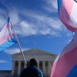 Um manifestante segura duas bandeiras do orgulho transgênero durante um protesto em frente à Suprema Corte dos EUA.