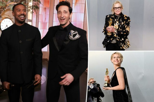 Jessie Buckley segurando uma estatueta dourada do Oscar enquanto fotógrafos tiram fotos.