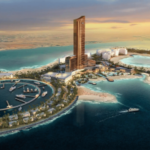 A construção do projeto de resort Wynn Al Marjan Island, nos Emirados Árabes Unidos, é retomada em meio às tensões no Irã. Renderização aérea do resort Wynn Al Marjan Island em Ras Al Khaimah, mostrando uma alta torre de hotel de bronze cercada por praias, piscinas e uma marina circular com iates nas águas azul-turquesa do Golfo ao pôr do sol.