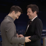 Dois homens ficam de frente um para o outro, rindo.