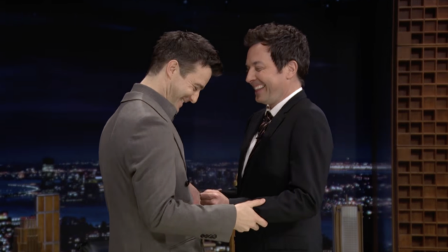 Dois homens ficam de frente um para o outro, rindo.