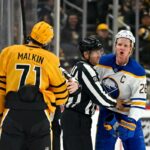 Rasmus Dahlin do Buffalo Sabres e Evgeni Malkin do Pittsburgh Penguins são separados por um árbitro durante um jogo de hóquei.